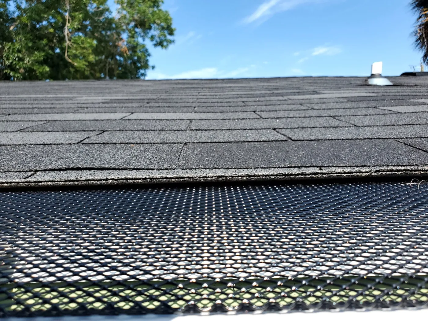 A black micro-mesh gutter guard installed along a roof edge